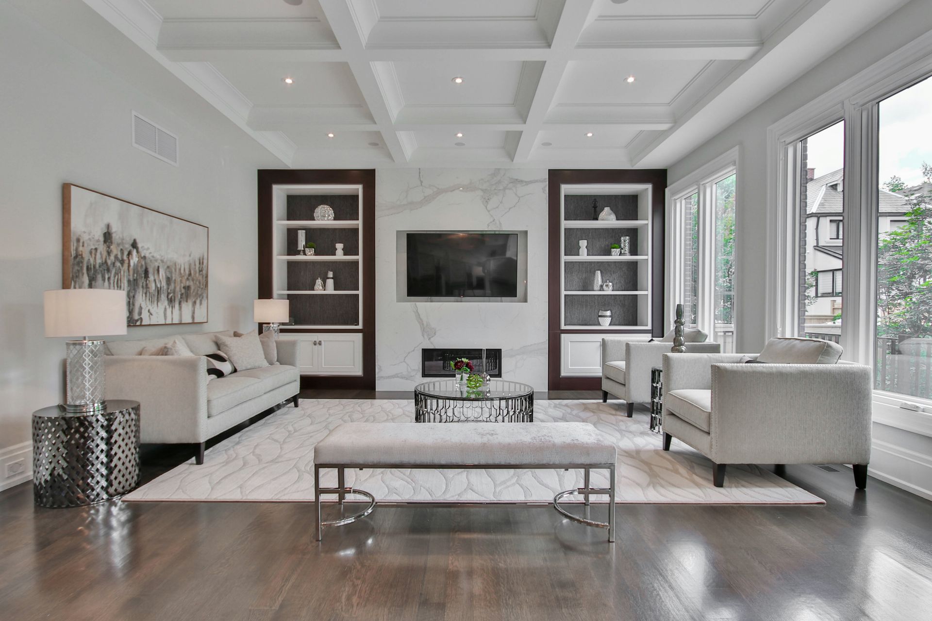 A living room with a marble fireplace, white sofas, and dark wood shelving